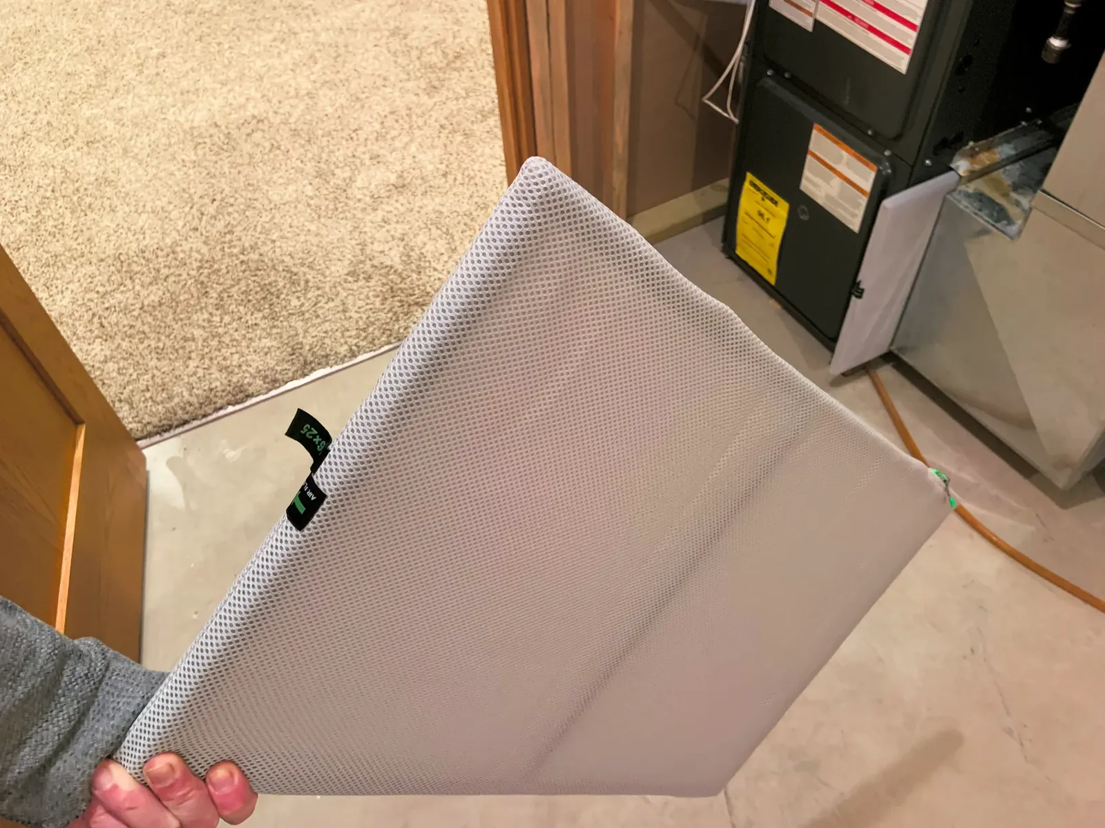 16x25 air filter being slid out of the return beside an upflow gas furnace